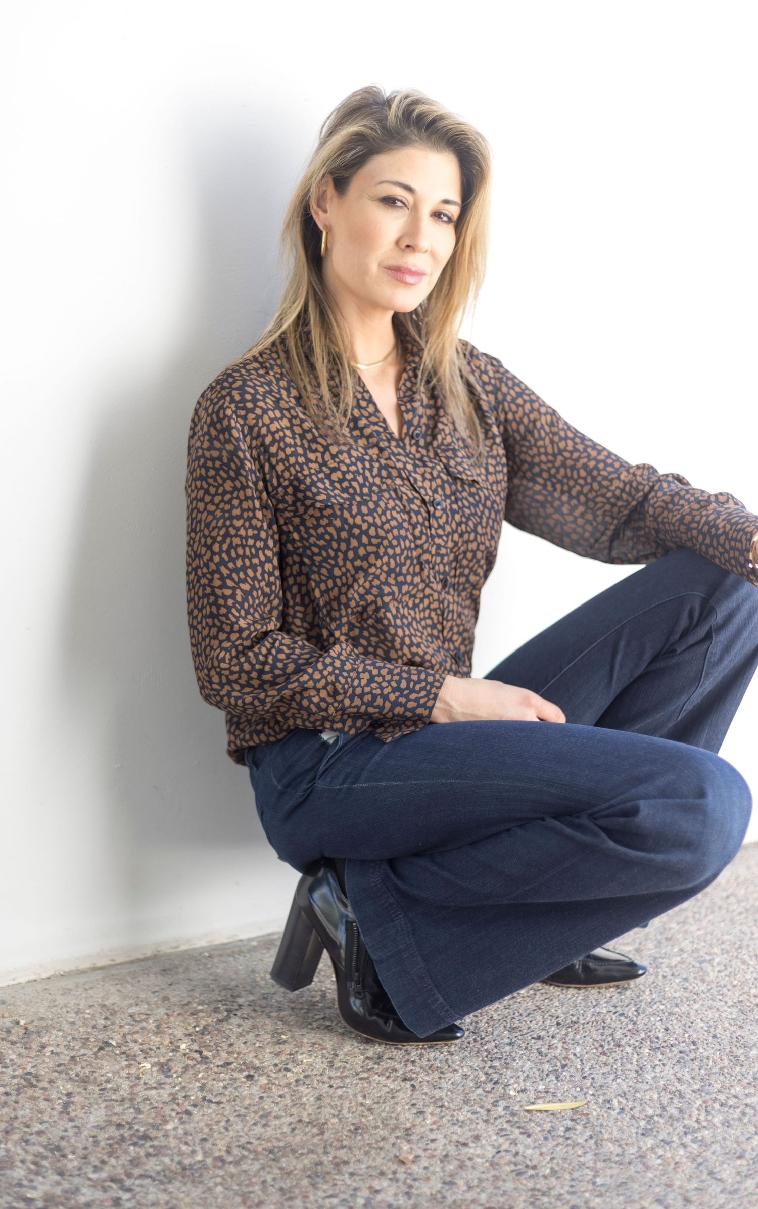 Chic leopard print blouse paired with dark denim jeans in studio setting.
