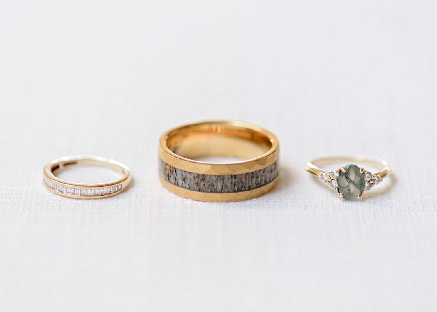 Three wedding rings arranged on white surface showcasing different styles and stones.