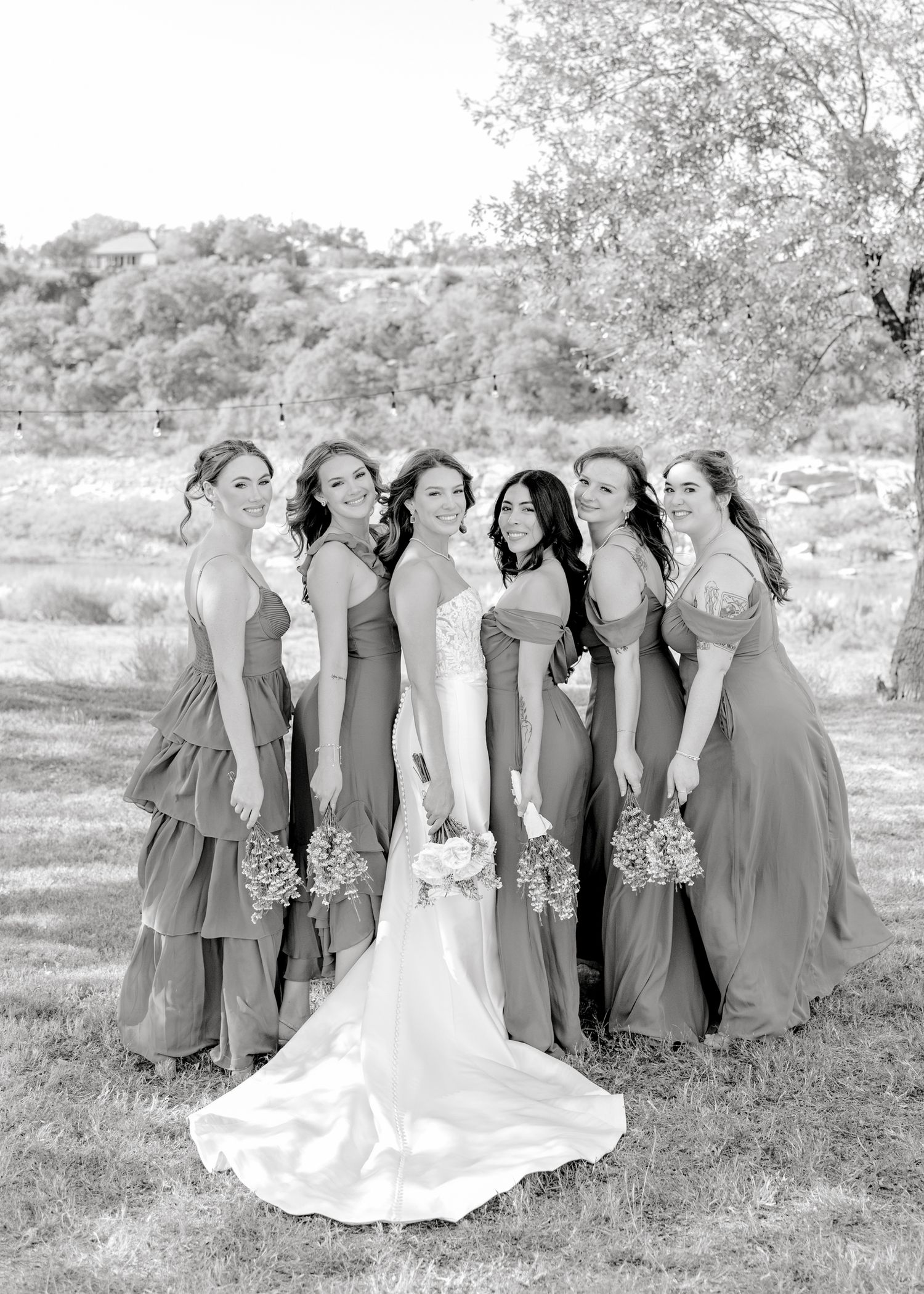 Black and white portrait of bridal party wearing matching gowns against a scenic backdrop.