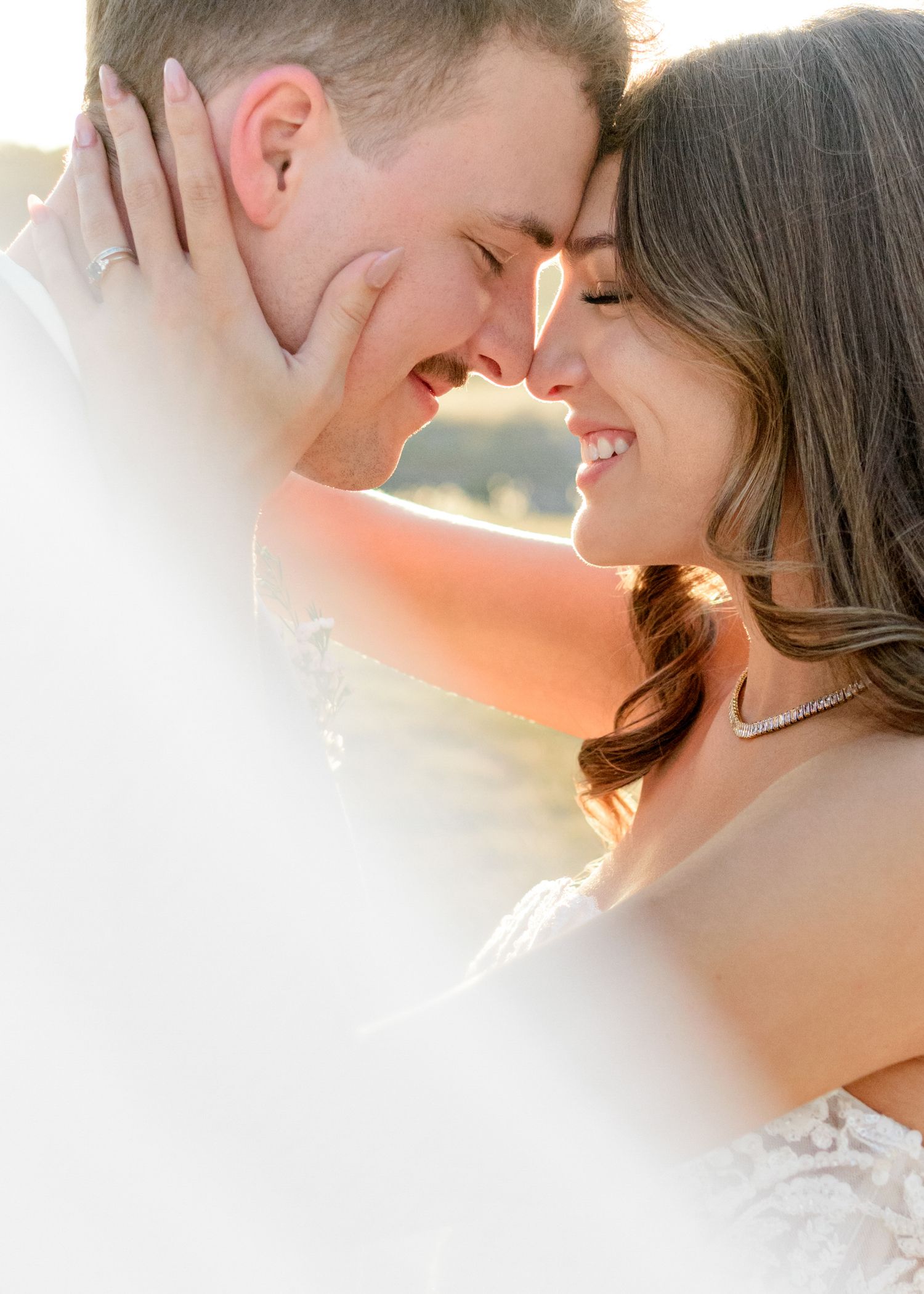 Intimate sunset wedding portrait capturing tender moment between newlyweds.