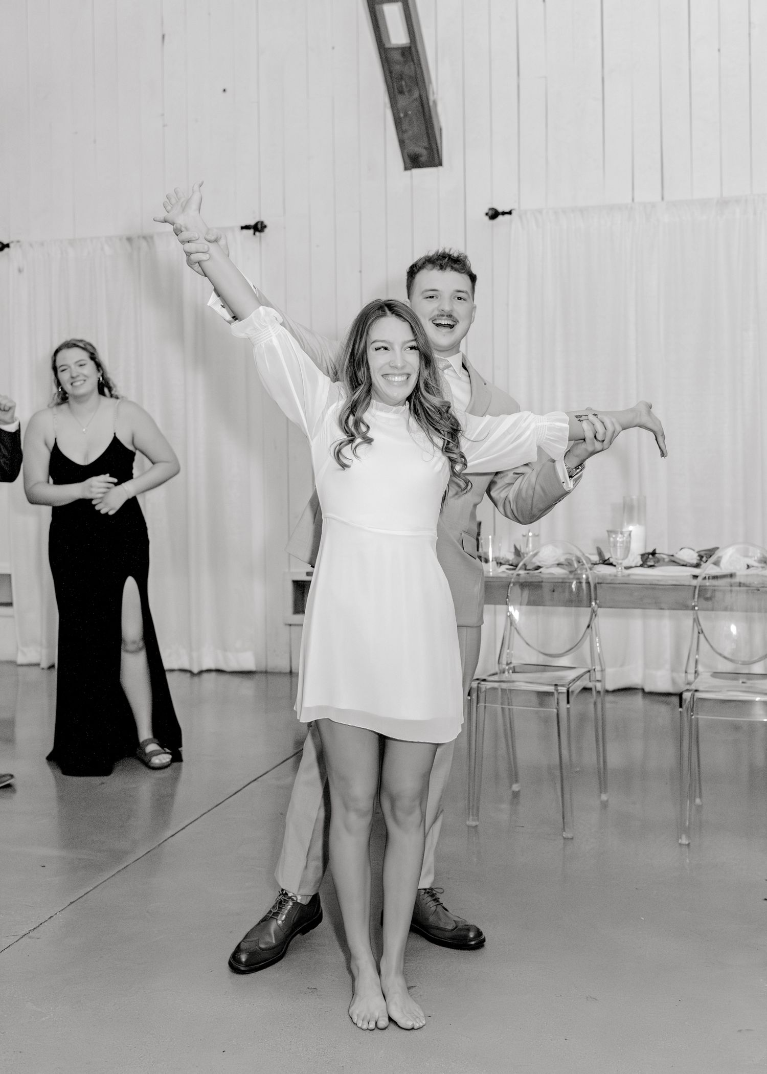 Wedding celebration candid moment in a bright reception hall with white walls.