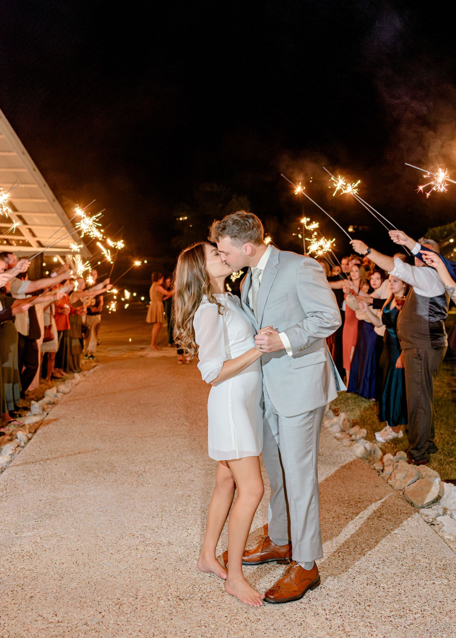 Romantic sparkler exit for newlyweds outside wedding venue at night.