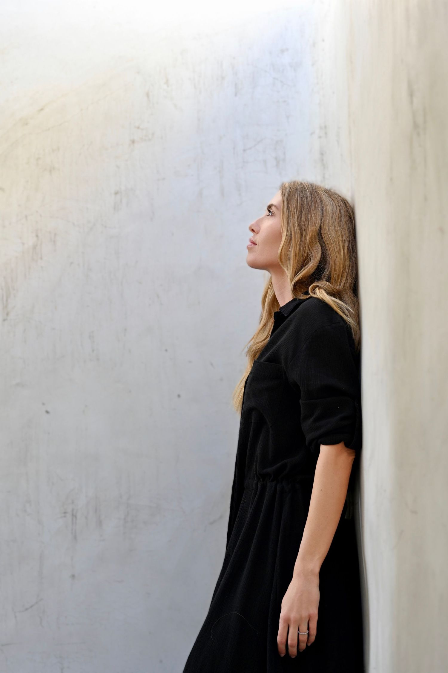 Artistic profile shots against white wall showing contemplative poses in black dress.