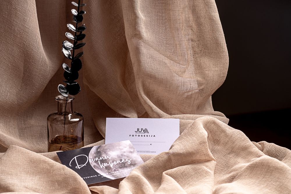 Elegant white business cards displayed on beige linen with glass vase and eucalyptus branch.