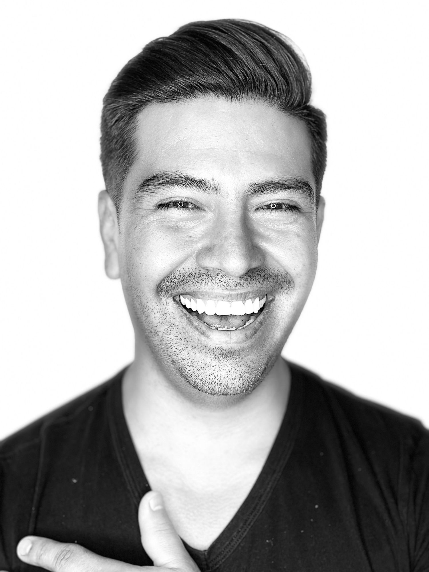 A black and white photo collage showing four similar headshots of someone smiling against a whitebackground.