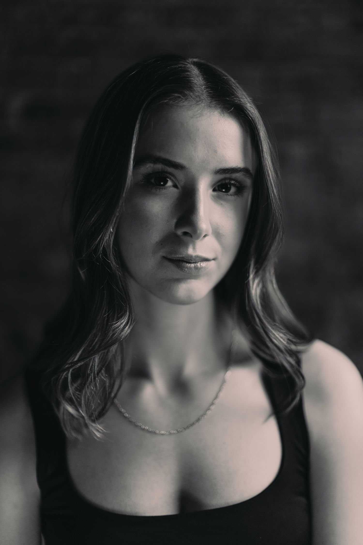 Dramatic black and white portrait series showing a person in dark lighting with subtle shadows and expressions.