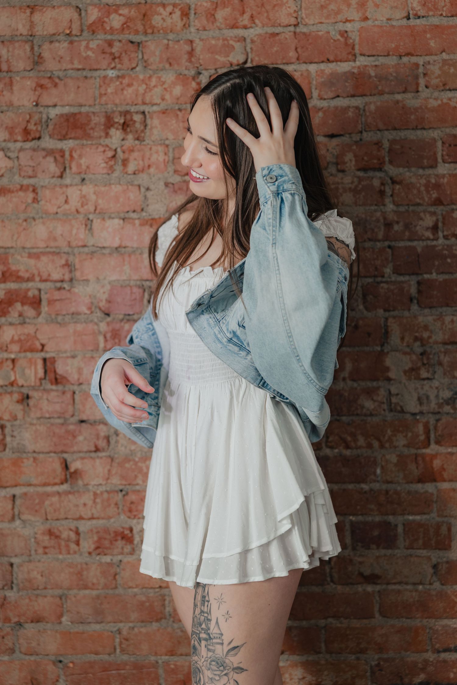 Four sequential photos show a romantic embrace against a rustic brick wall backdrop in casual denim and white attire.
