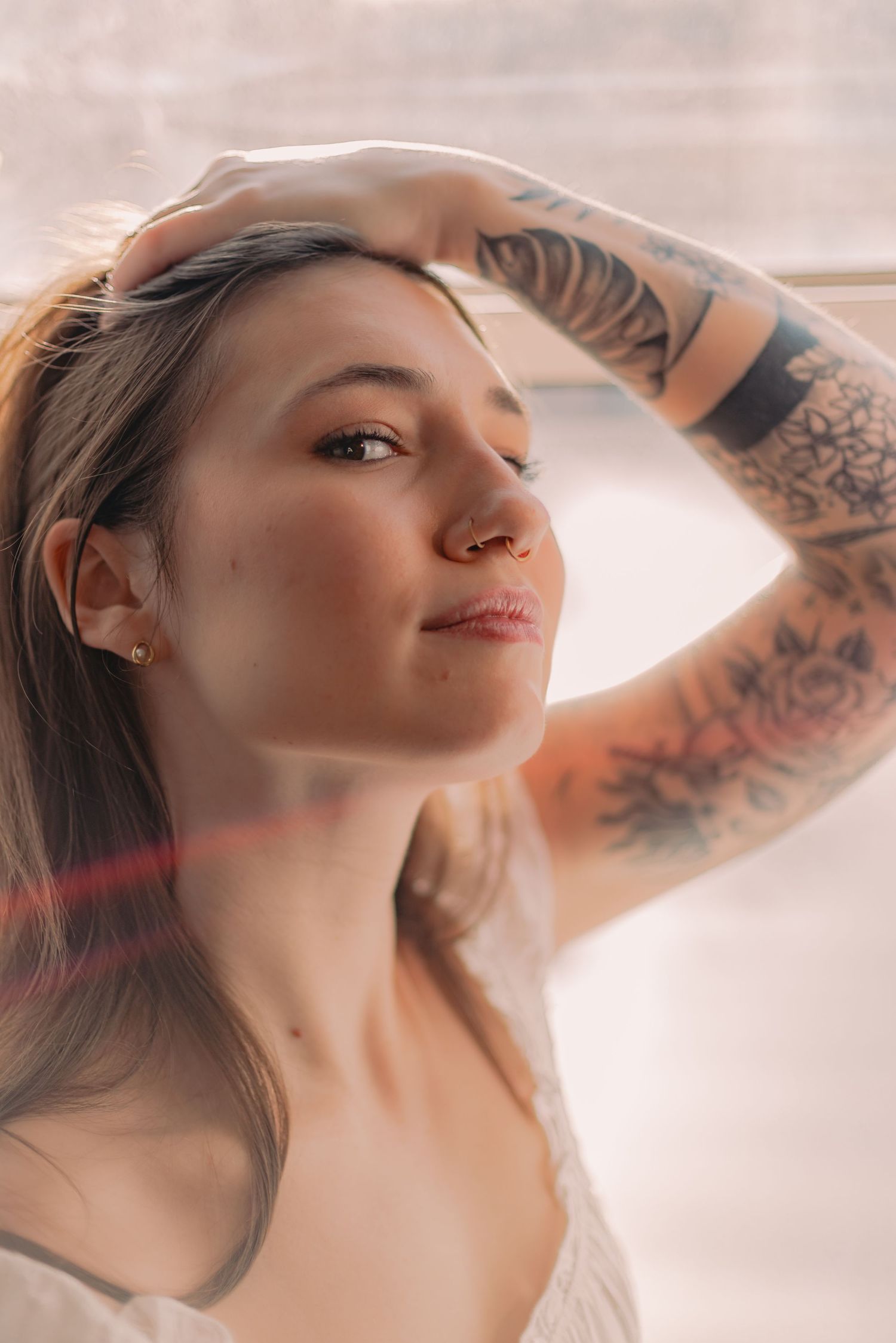 Artistic portrait series showing a person with tattoos in soft lighting posing with graceful neck movements.
