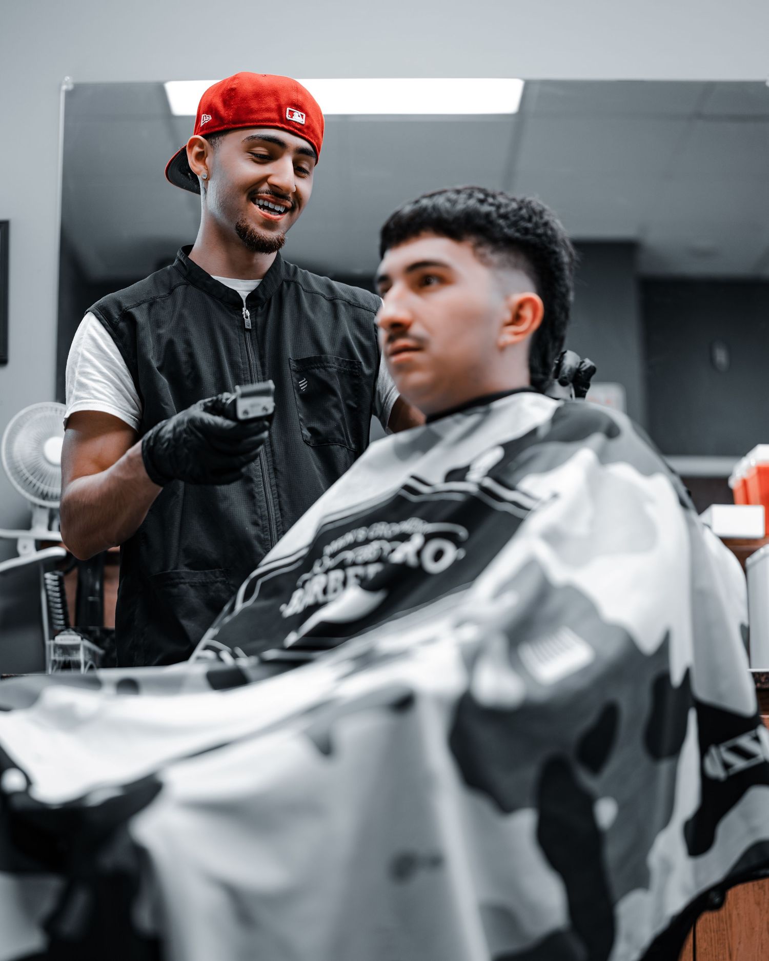 Professional barber cutting client's hair with scissors in modern barbershop with monochromatic color scheme.