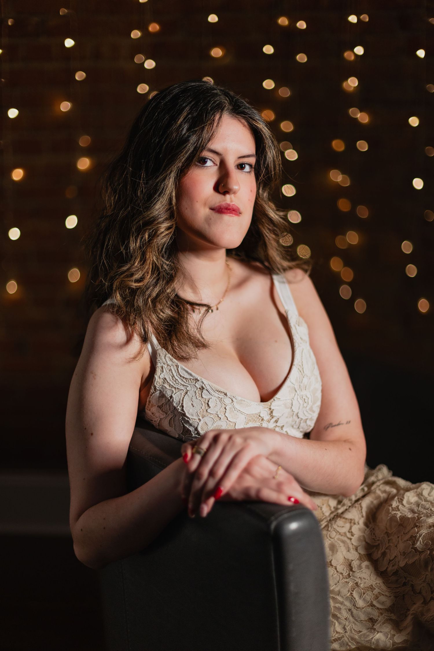 Artistic boudoir portrait series with bokeh lights and black and cream colored styling against dark background.