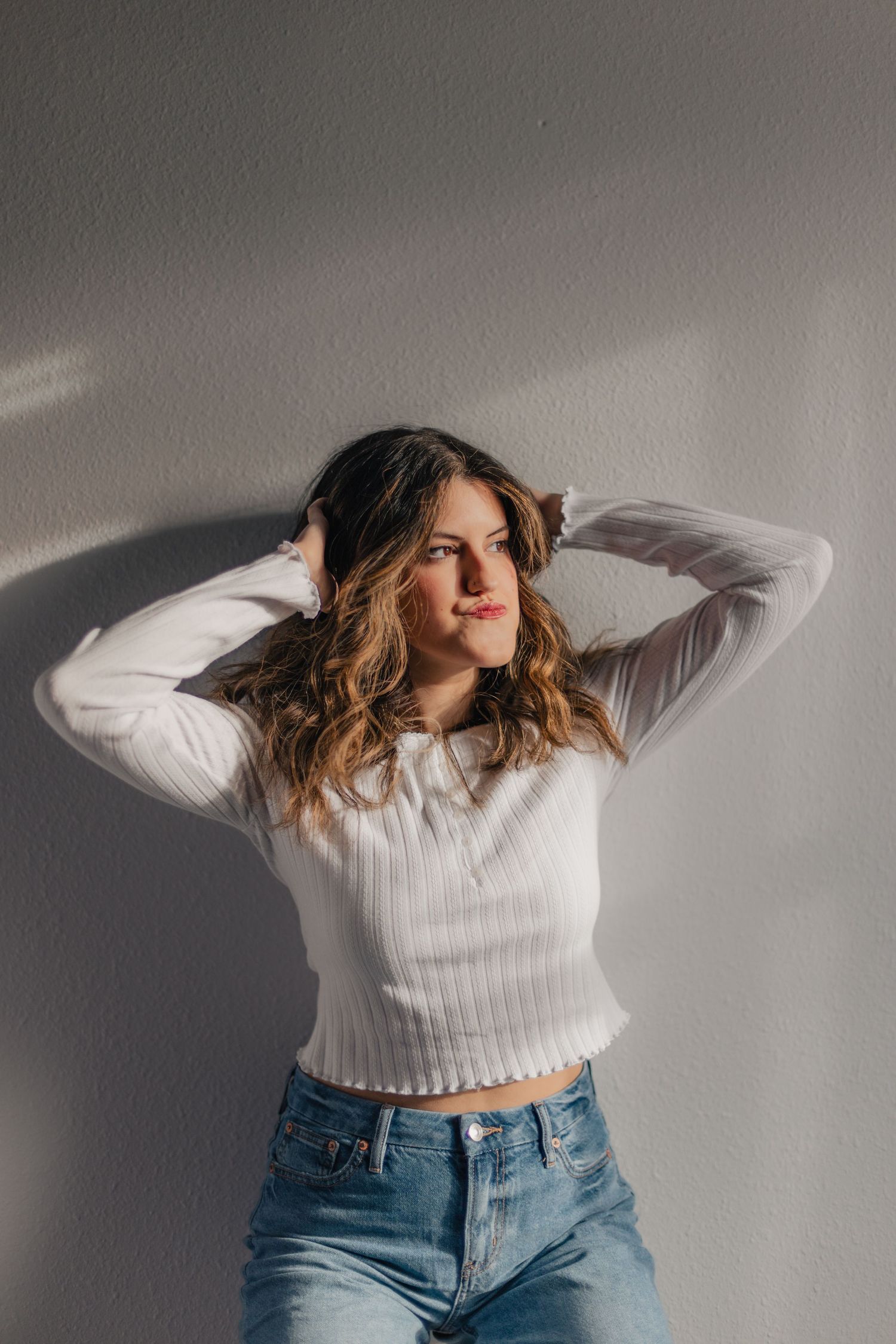 A person in a white cropped sweater and jeans dances expressively against a gray background in a photo sequence.