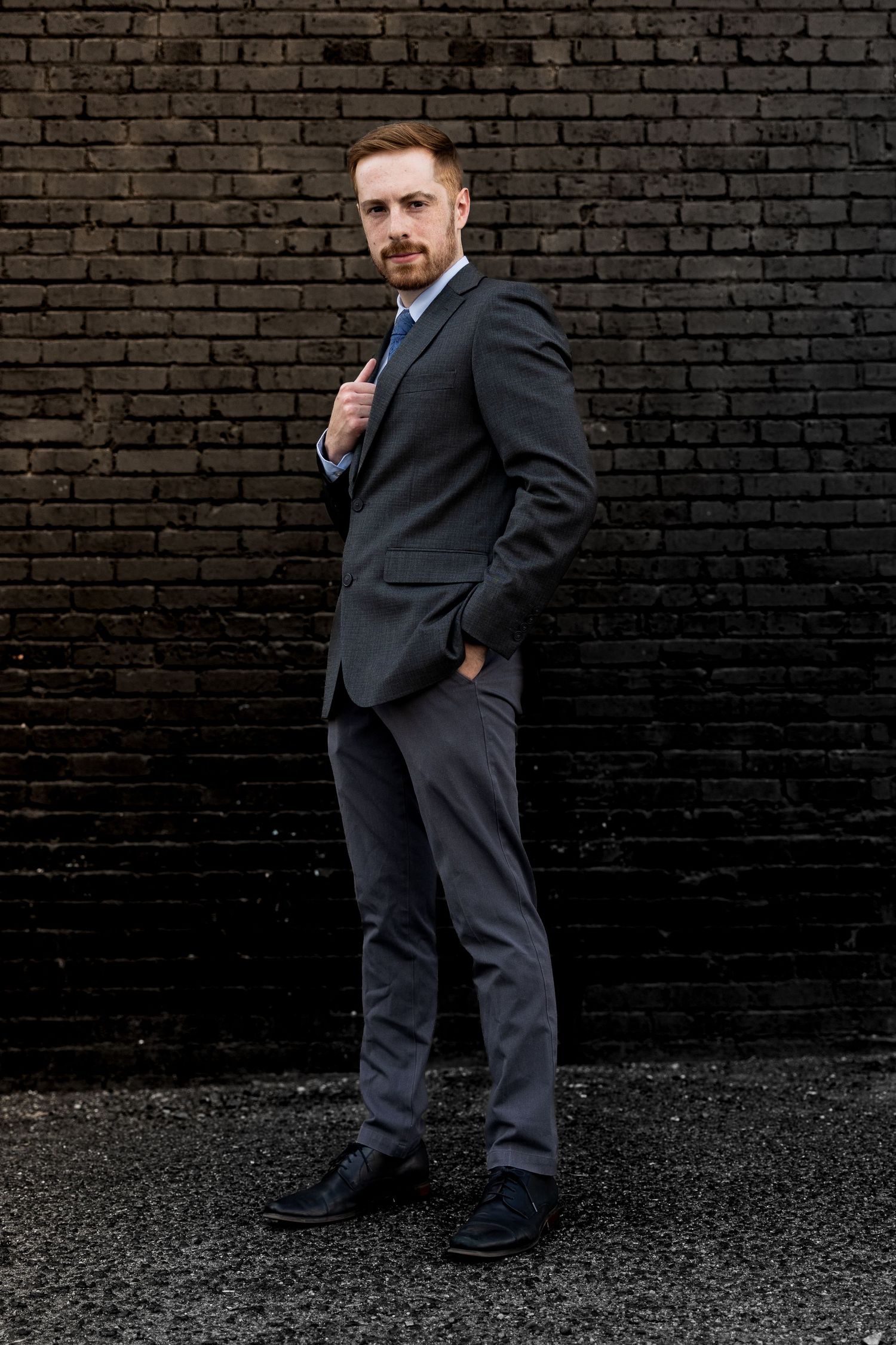 A series of black and white photos showing a person in a dark suit posing against a brick wall background.