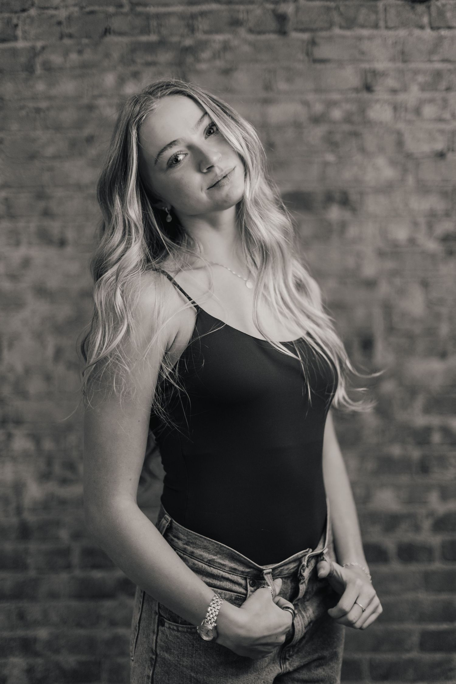 Black and white portrait series against brick wall showing artistic movement and dramatic poses in casual attire.