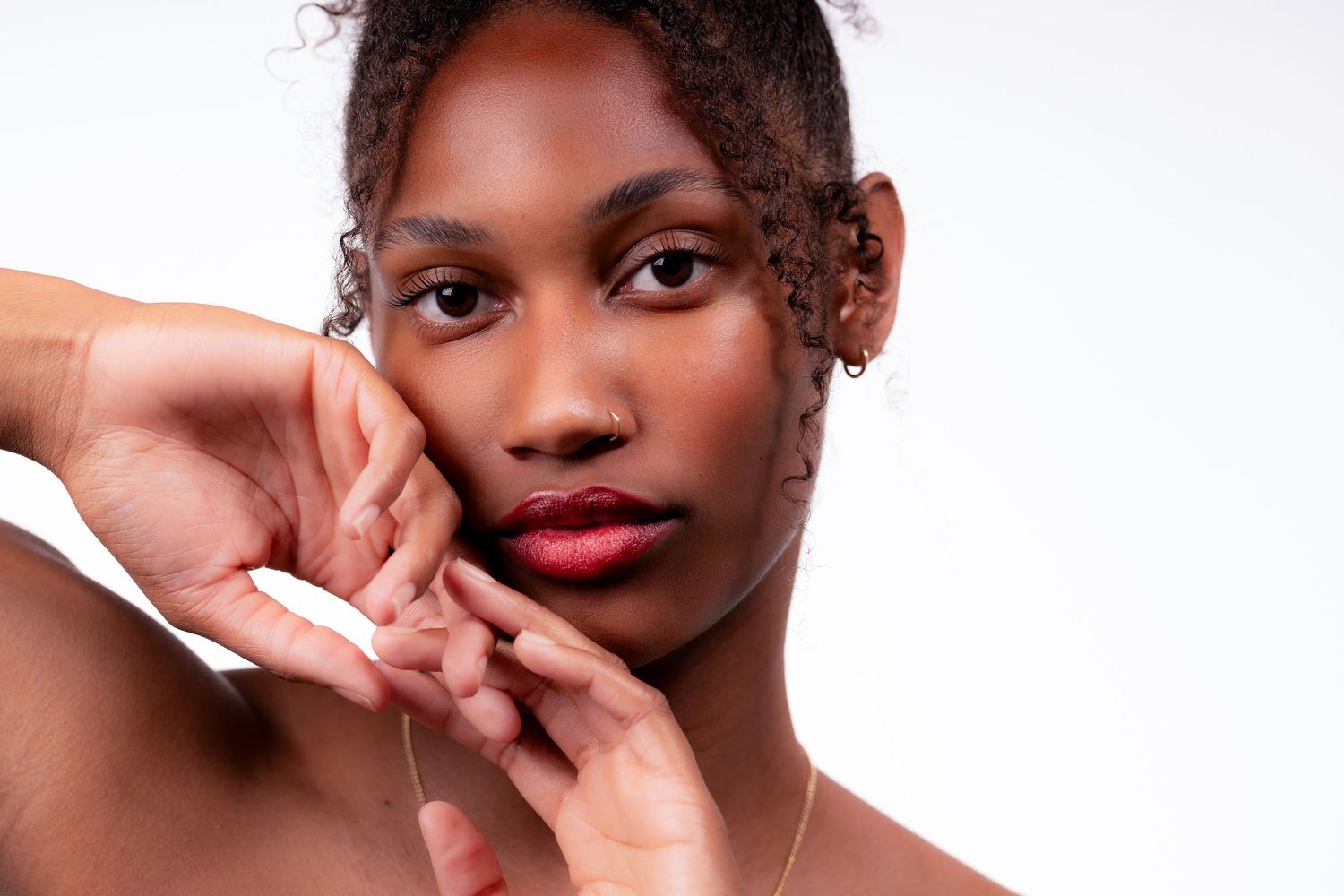 A collection of four beauty portraits showing close-up shots with red lipstick and natural curly hair.