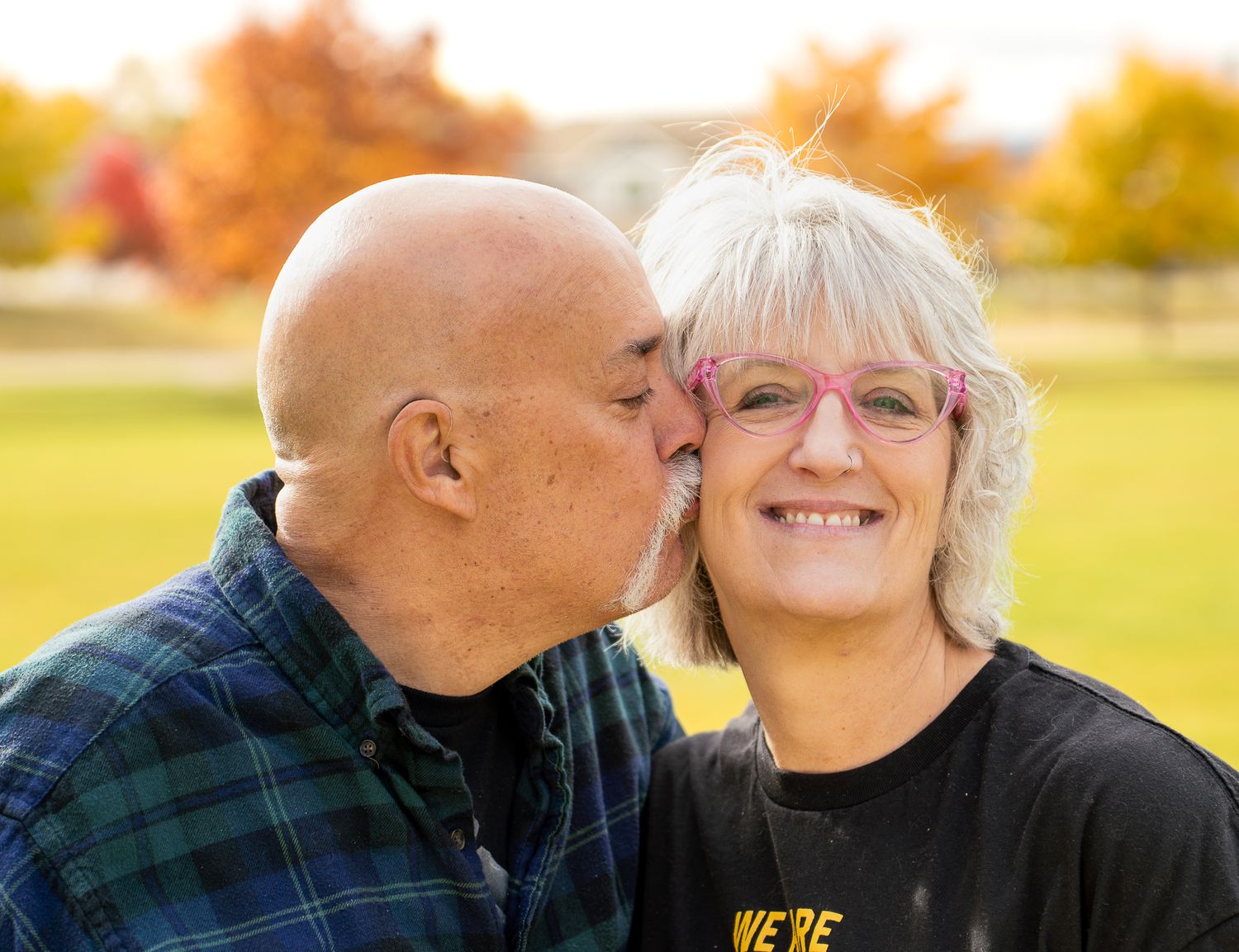 A couple shares tender moments together in an autumn outdoor setting during a golden hour photo session.