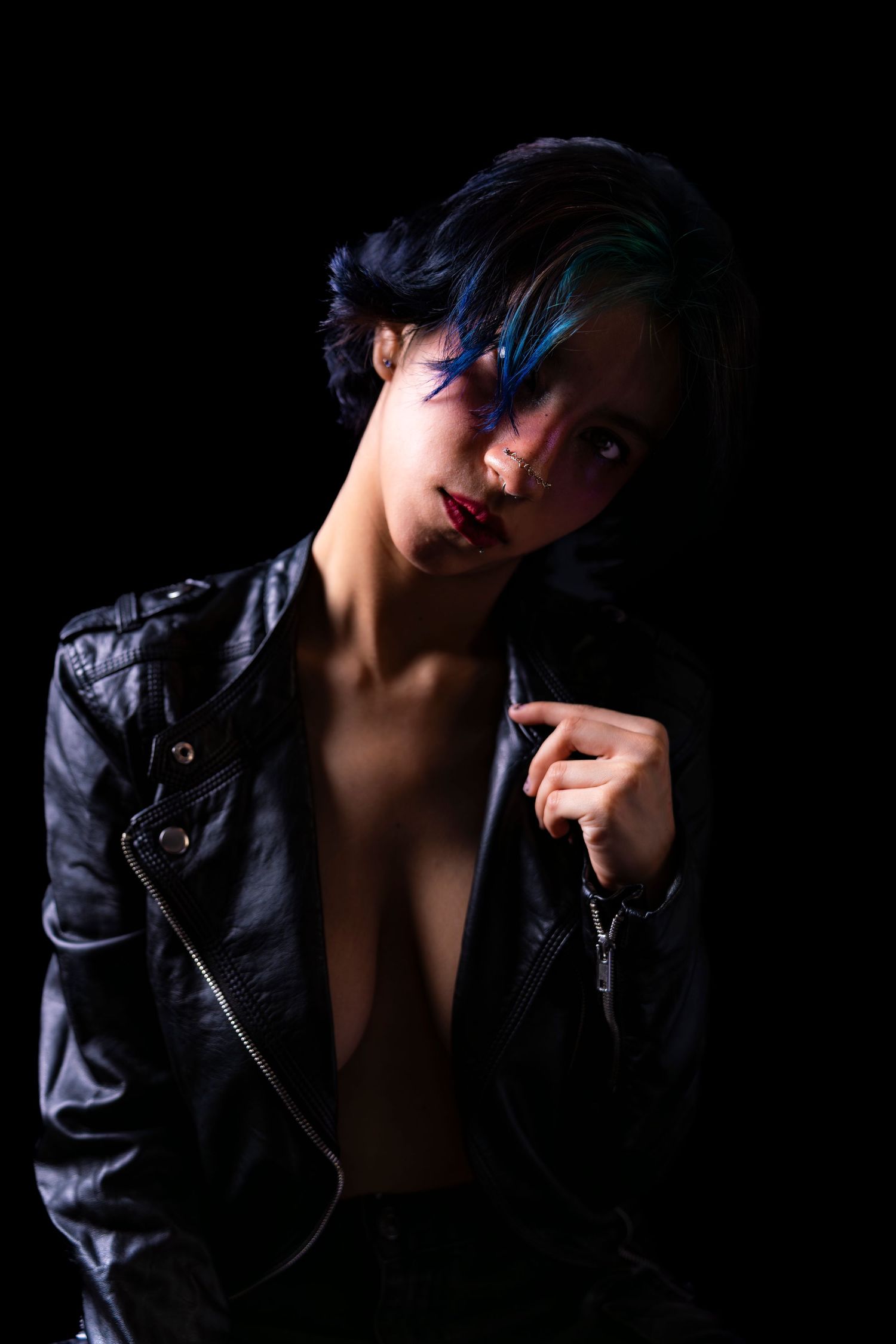 Dramatic portrait series in low key lighting features figure in black leather jacket against dark background.