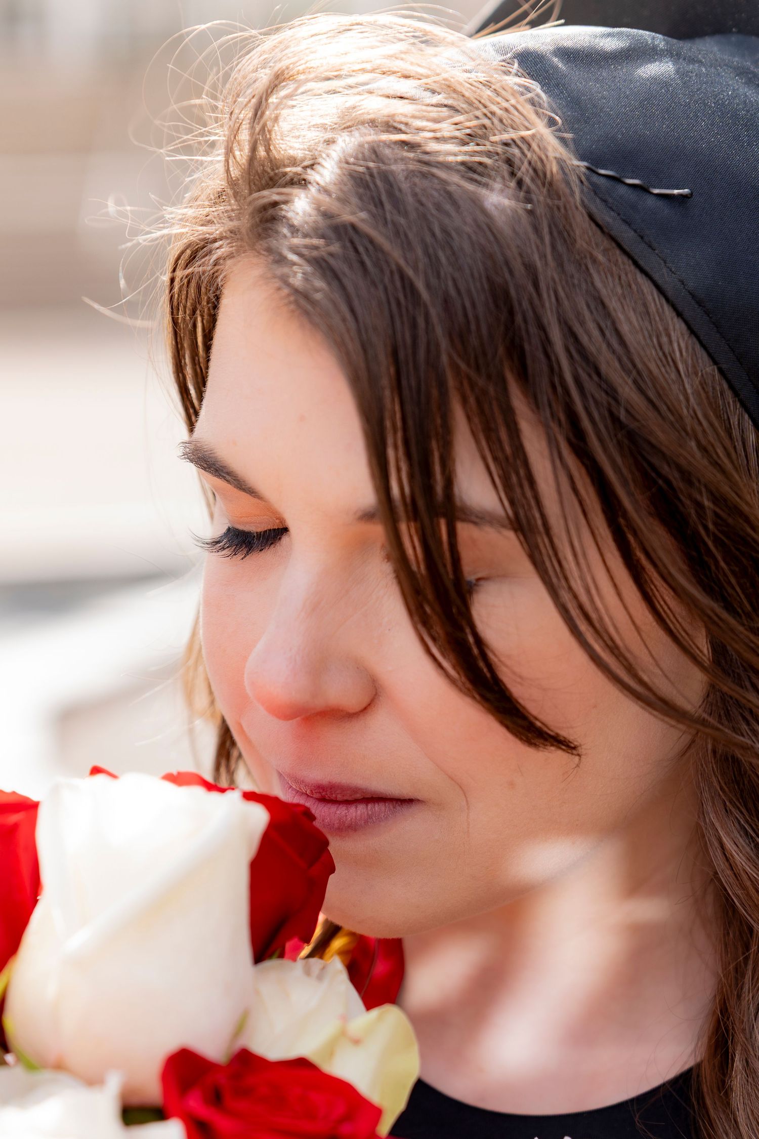 A person in black clothing looks down with a soft smile in a series of close-up profile shots.