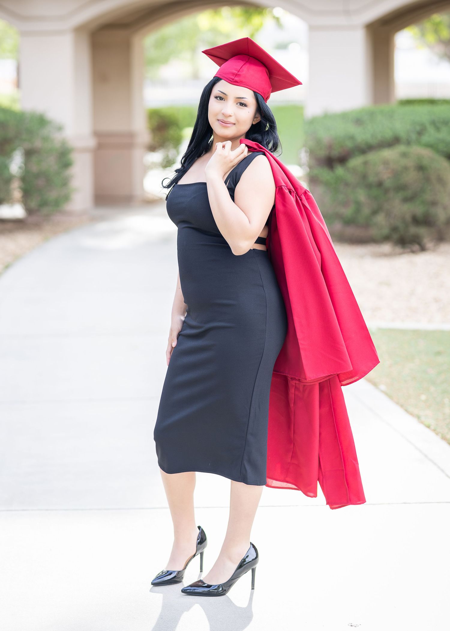 A professional photographer photographs a female senior for her senior portraits. Using natural light, photographer poses female for photo.