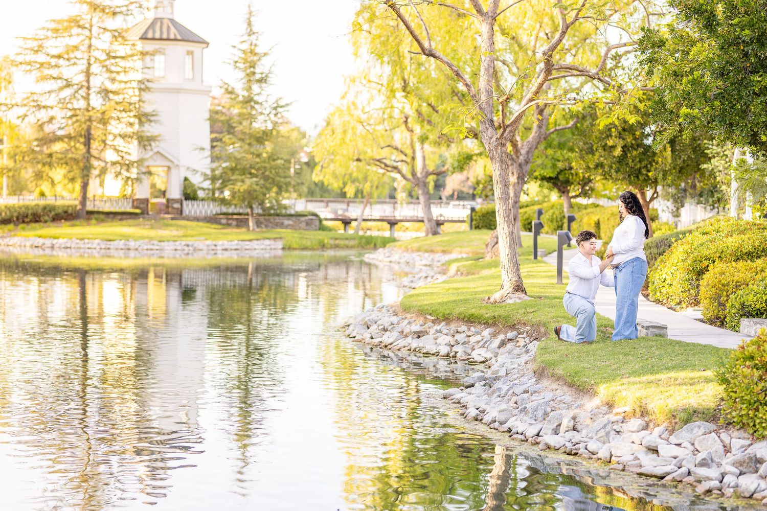 Maternity Photophoto. A couple poses together next to a lake and a light tower as the sun sets. Photographer uses natural lighting