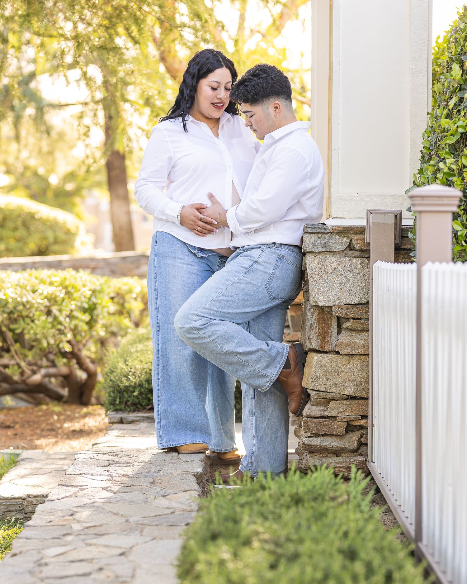 A couple poses for maternity photos. The photographer poses couple as the sun is setting, using natural light. Photographer from Palmdale CA