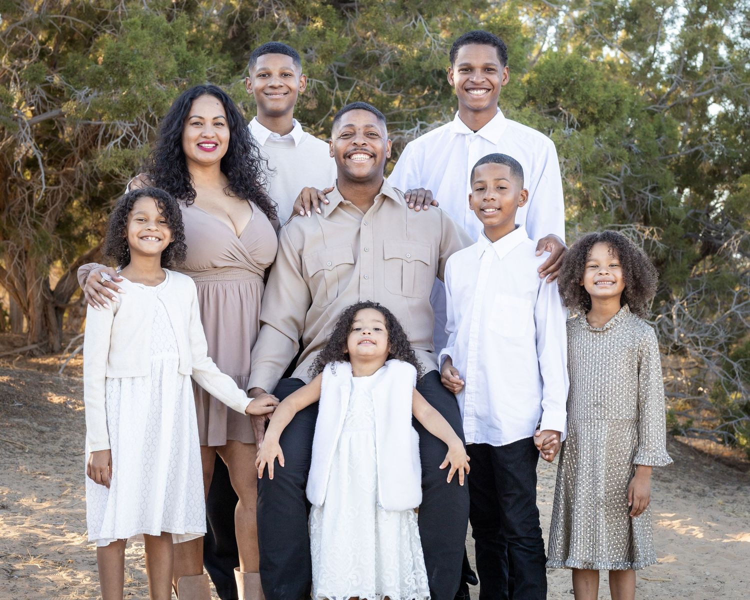 A family portrait with several family members standing closely together outdoors.