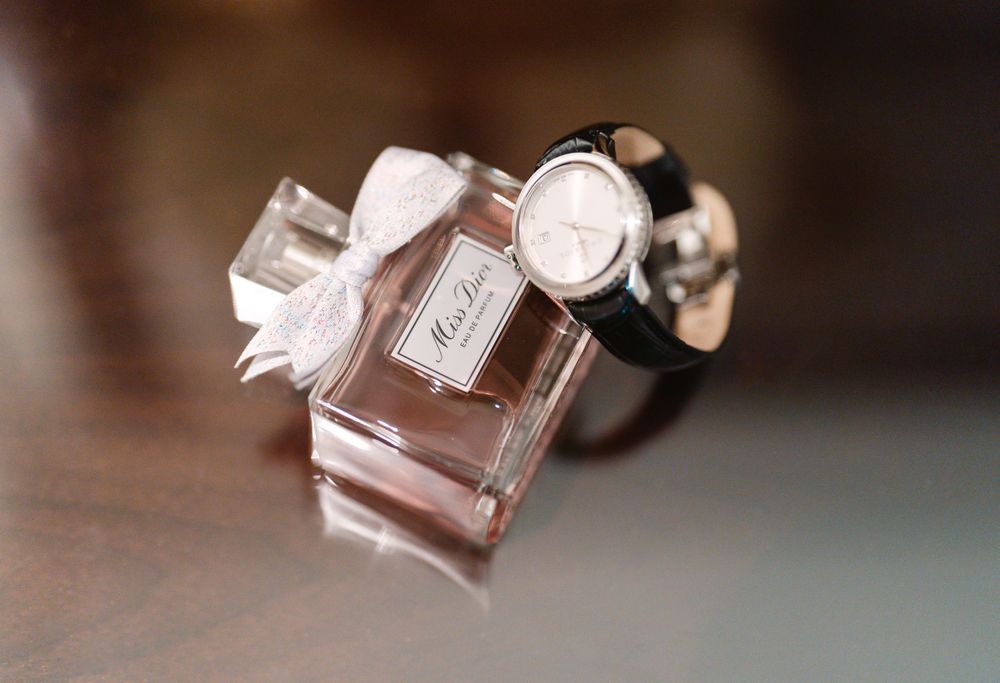 A luxurious pink perfume bottle with bow detail on a reflective surface.