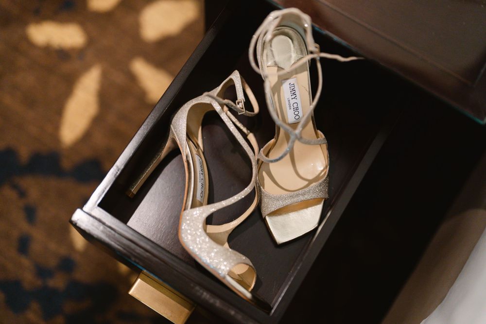 Sparkly silver wedding heels with delicate straps photographed on a dark surface.