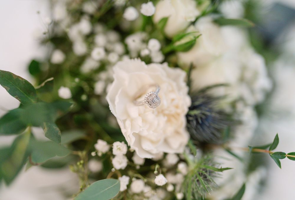 Close-up detail of white rose and baby's breath floral arrangement with soft bokeh background.