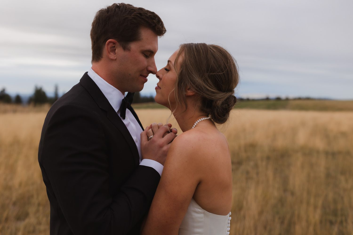 An intimate moment shared between newlyweds in a rustic field setting. Spokane wedding photographer.