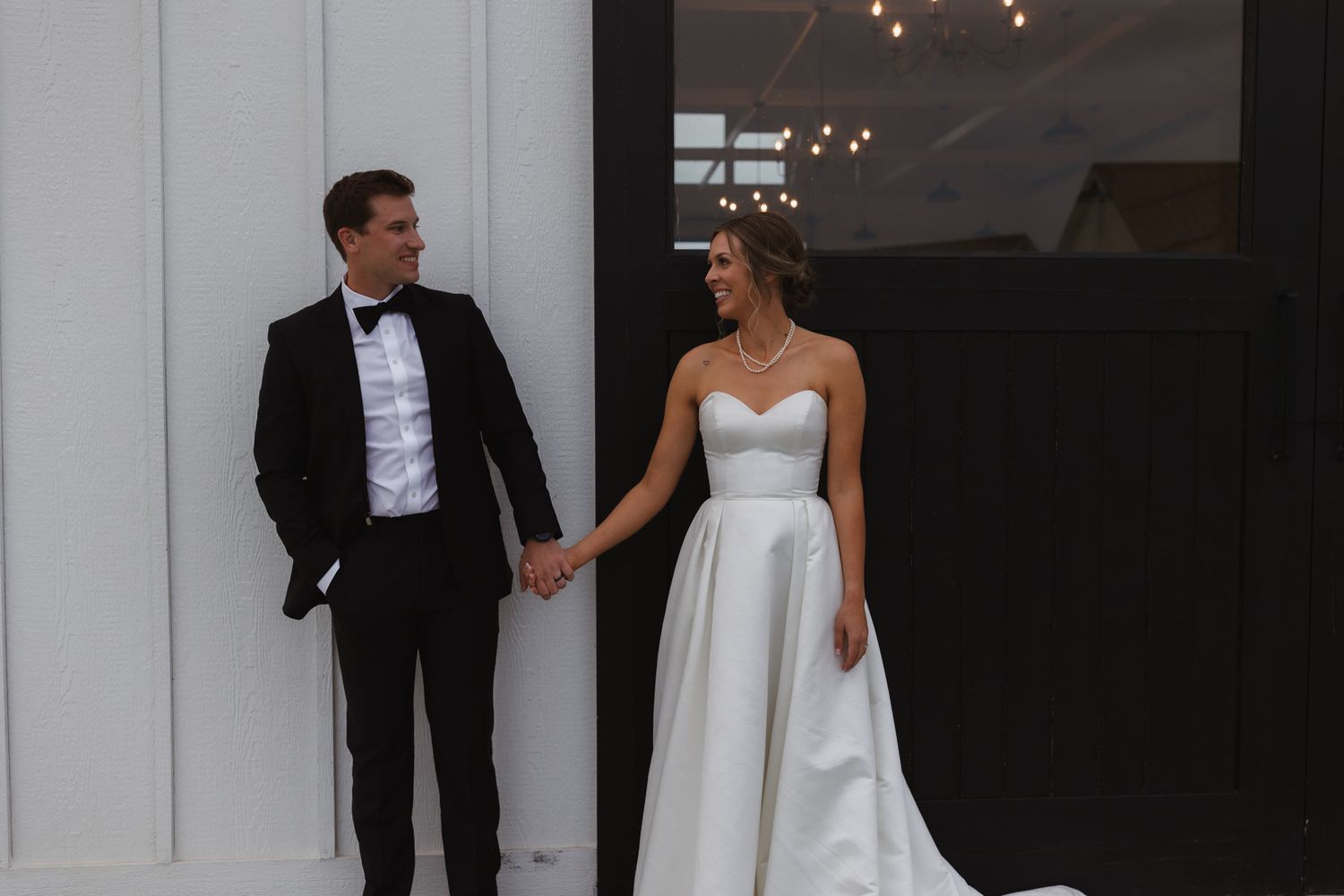 A formal couple poses against a modern white and black wall backdrop in wedding attire. Spokane wedding photographer.