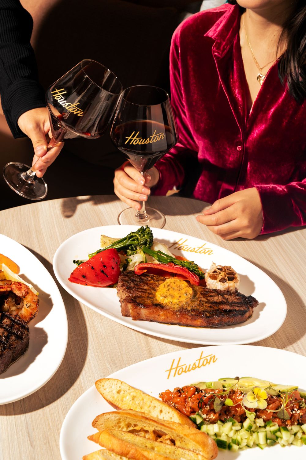 Elegant steakhouse dinner setting with red wine glasses and plated ribeye steak. Mtlshutter photography