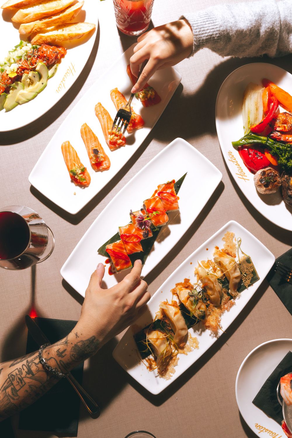 Overhead view of various appetizers and entrees on white plates with wine glasses. Mtlshutter photography