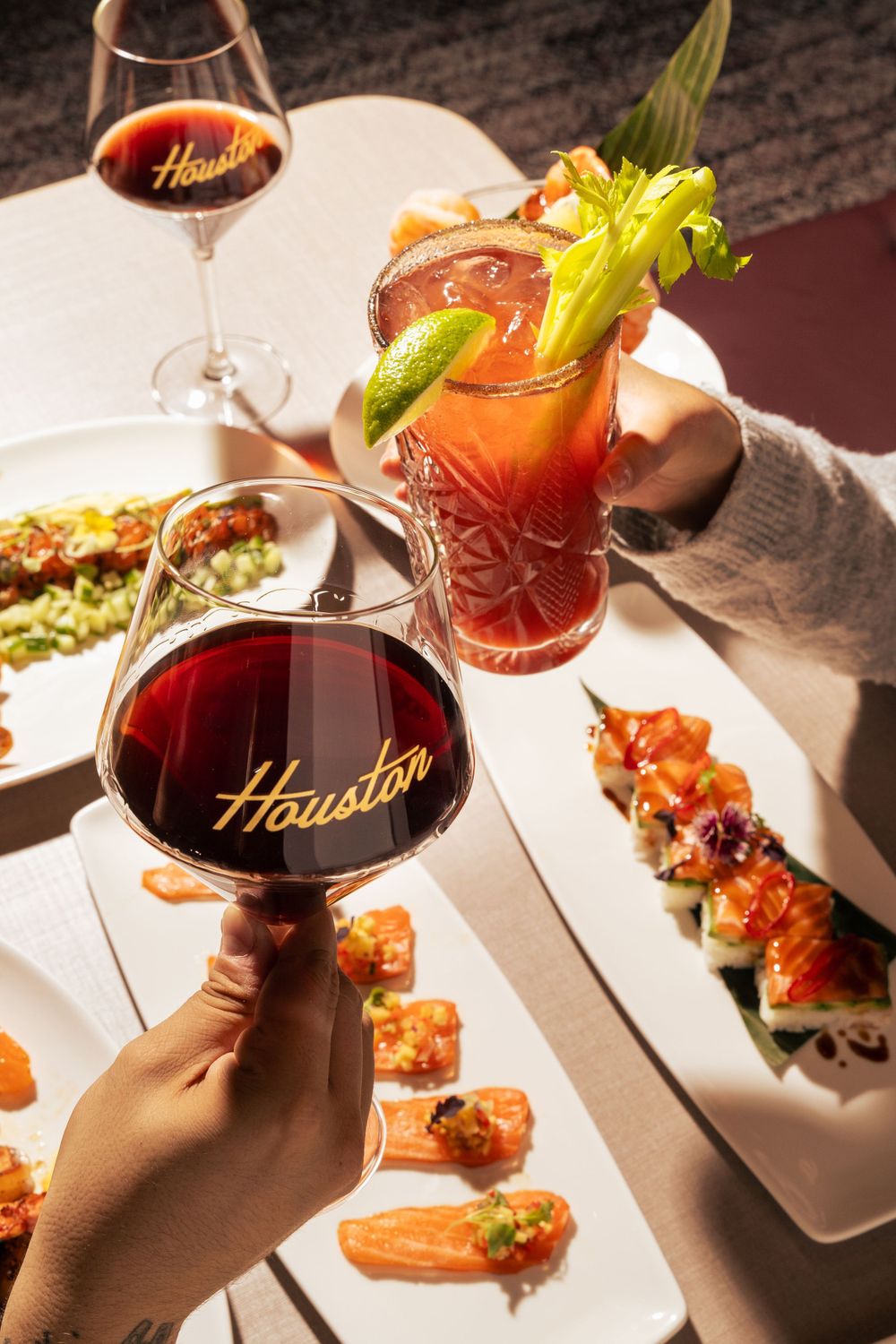 Wine glasses and cocktails alongside elegantly plated appetizers on a white tablecloth at Houston restaurant. Mtlshutter photography