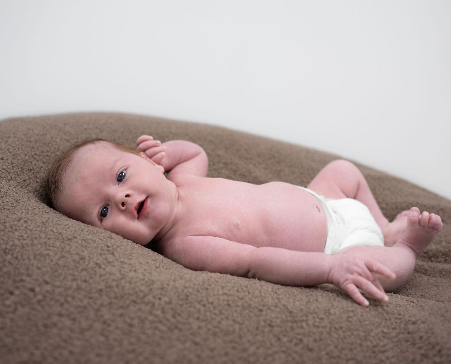 Newborn on a beanbag looking and smiling straight at the camera