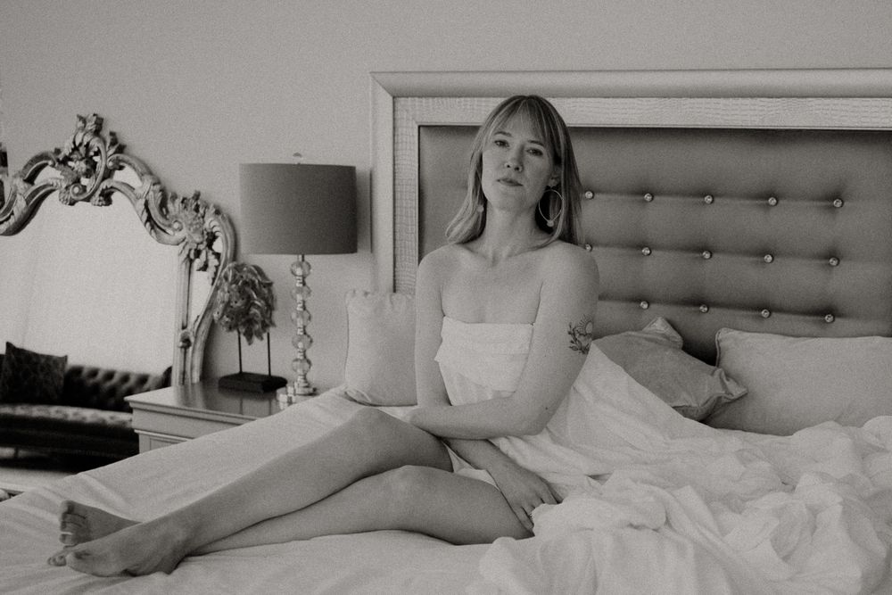 Classic boudoir portrait on an elegant tufted bed with vintage-inspired decor.