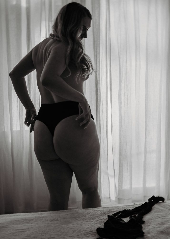 Artistic boudoir silhouette against window light.