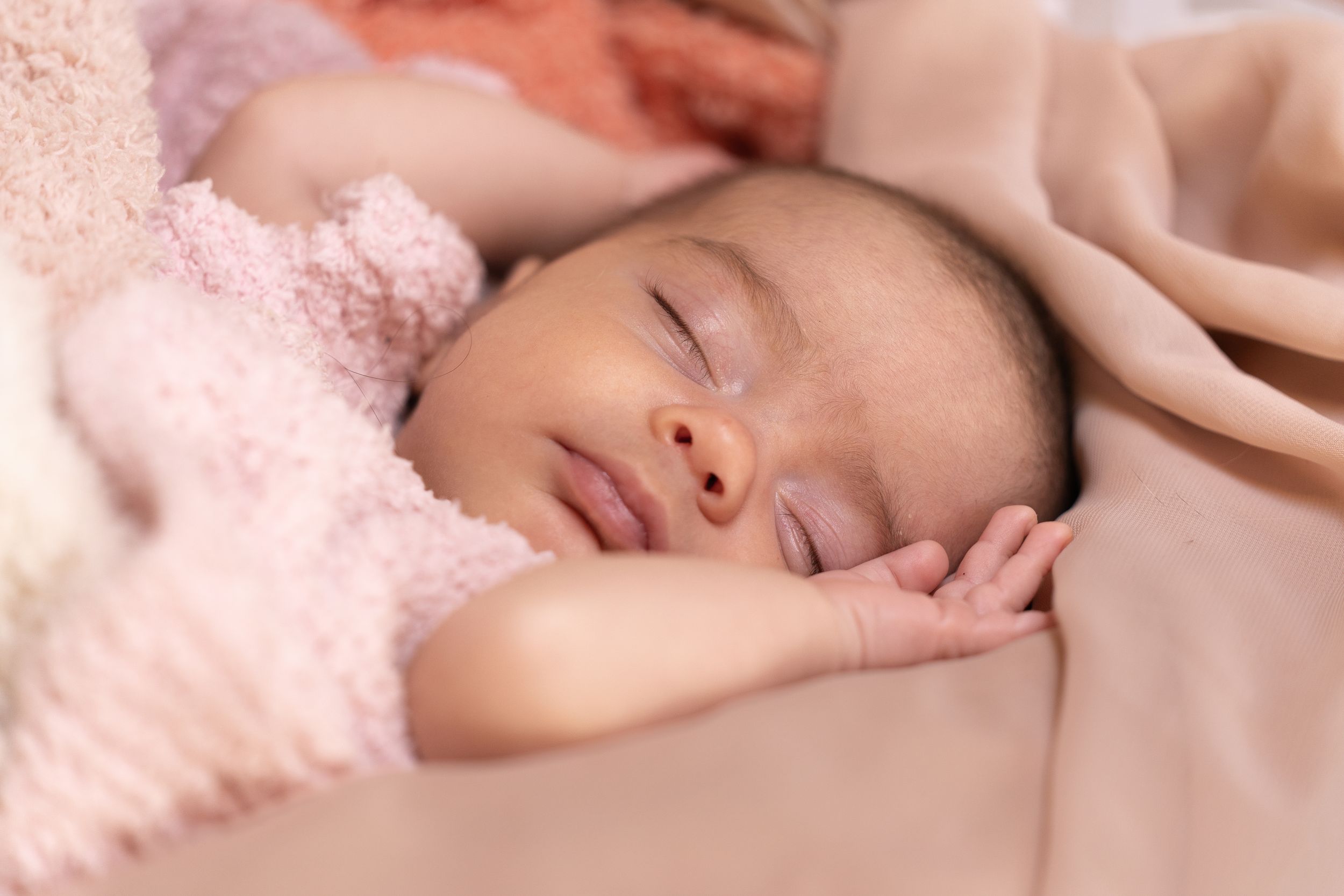 A sleeping baby wrapped in soft pink blankets.