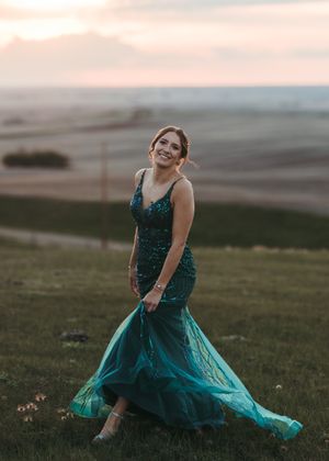 Woman in emerald mermaid sequin gown twirling on a hillside at golden hour. Senior grad photos. Graduation photos.