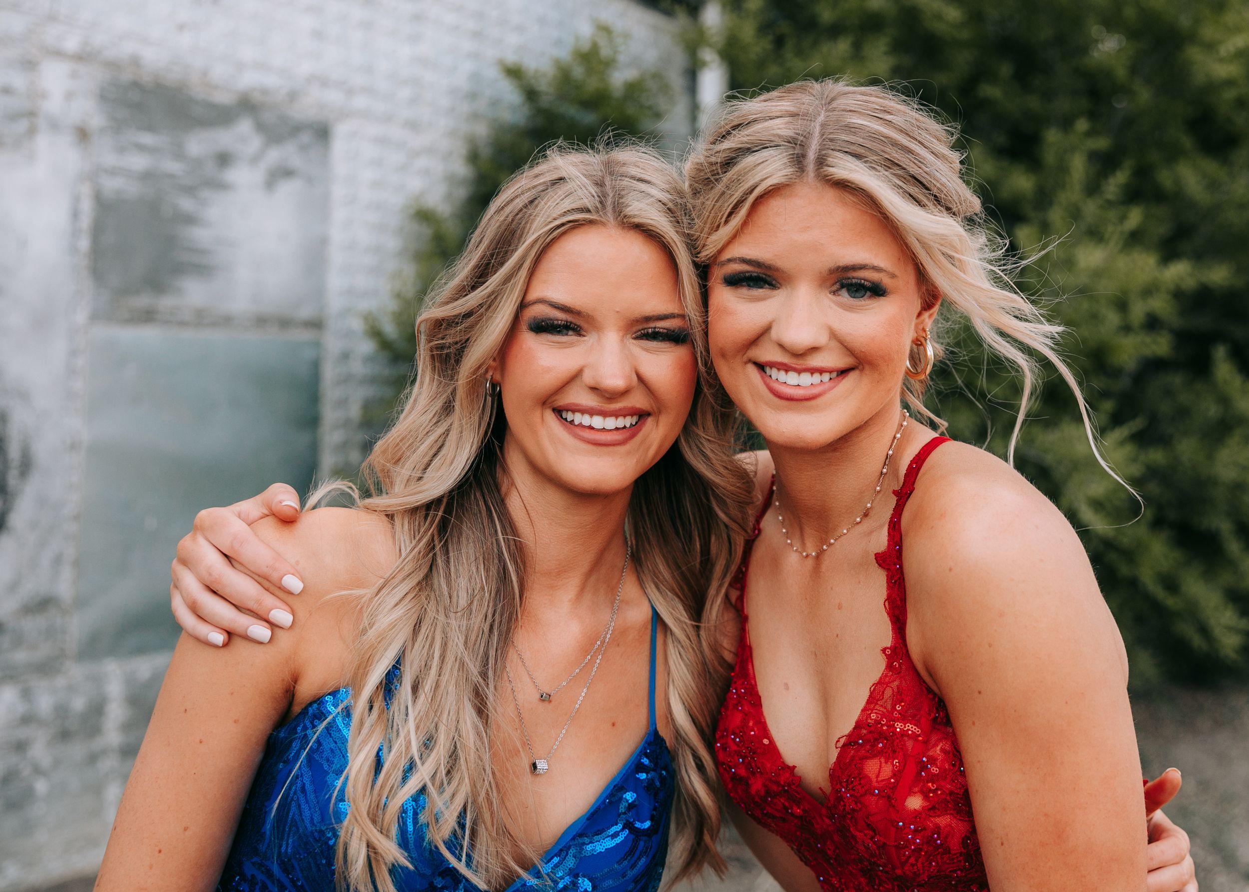 Two smiling girls in blue and red formal dresses. Senior grad photos. Graduation photos.