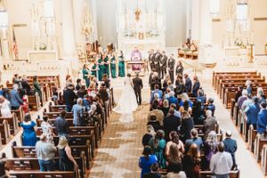 Wedding ceremony in a grand church with guests in blue attire filling the wooden pews. 
Alexandria, La Wedding