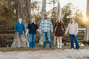 A casual group photo of five people standing against trees at golden hour.
