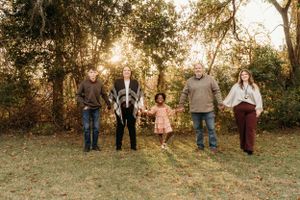 A family photo session at sunset in a grassy field with trees.