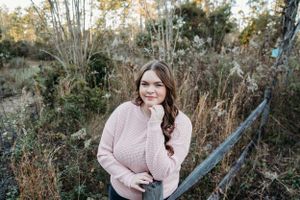 A portrait in an autumn setting with tall grass and trees in the background.