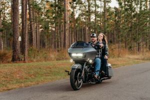 A motorcycle rider cruises down a forest road during golden hour.