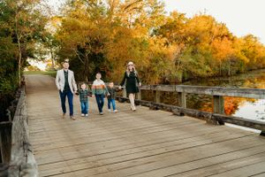 A group walking together on a wooden boardwalk surrounded by autumn trees with golden foliage.
