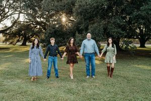 A group of people stand together in a grassy field at sunset creating a natural outdoor portrait scene.