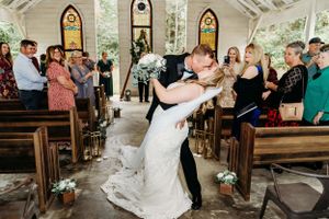A joyful first dance in a beautiful chapel with stained glass windows.