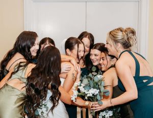 Bridesmaids in elegant dresses sharing an intimate moment with bouquets.