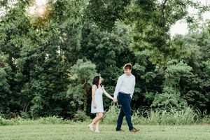 A couple walks together through a lush green garden during a sunny summer day.