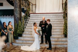 A wedding ceremony taking place on elegant white marble stairs adorned with greenery.